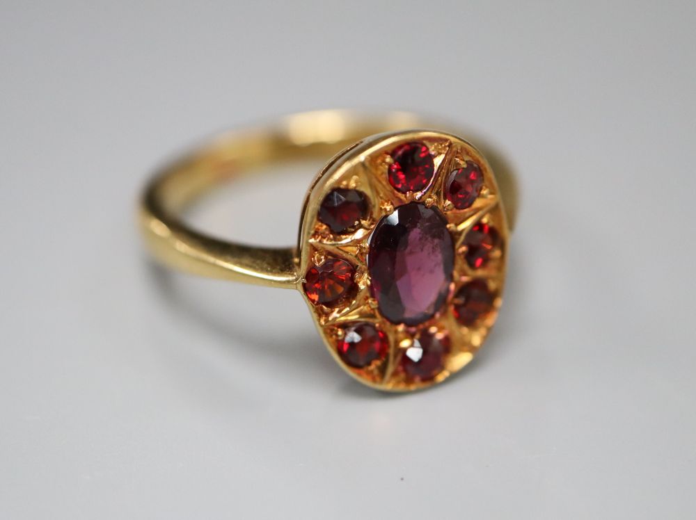 An 18ct and nine stone garnet oval cluster ring, size N, gross 4.4 grams.